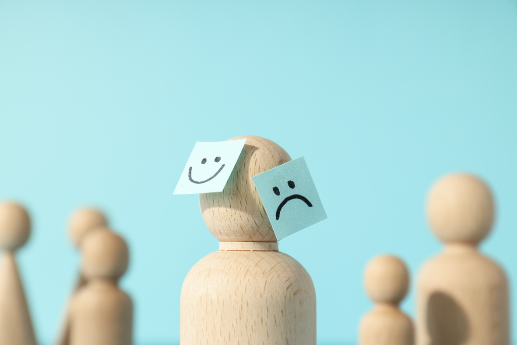 A wooden figure with a happy face on one side and a sad face on the other, depicting the mood swings associated with bipolar disorder. This highlights the importance of bipolar treatment in Thousand Oaks, CA.