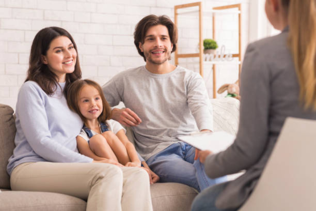 Smiling family sitting together on a couch with a therapist, receiving family therapy in Thousand Oaks, CA, promoting family bonds and understanding.