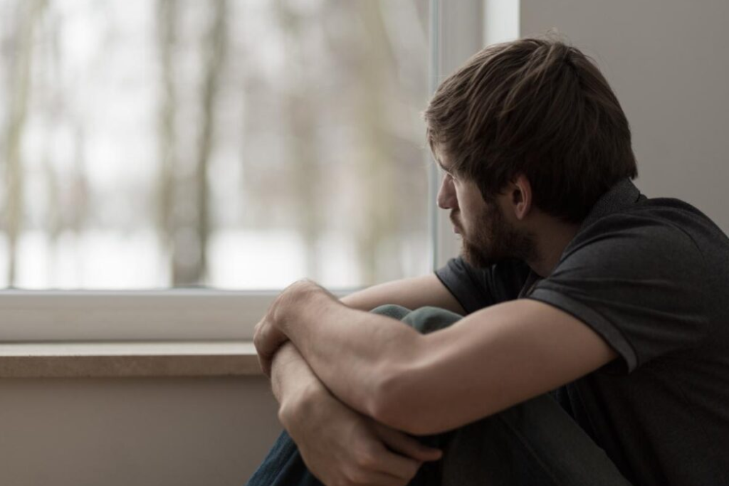 Man gazing out a window, reflecting on his need for opiate addiction treatment and recovery support.