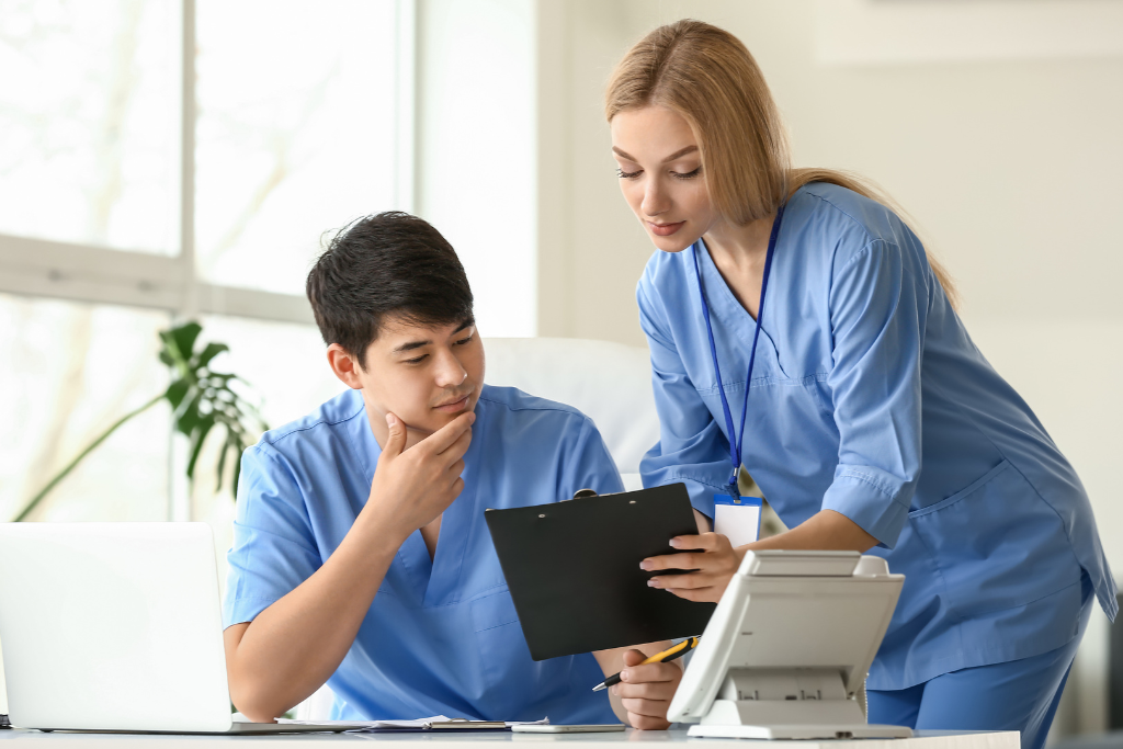 Two medical professionals in blue scrubs reviewing a clipboard, symbolizing teamwork in the MAT program Thousand Oaks CA.