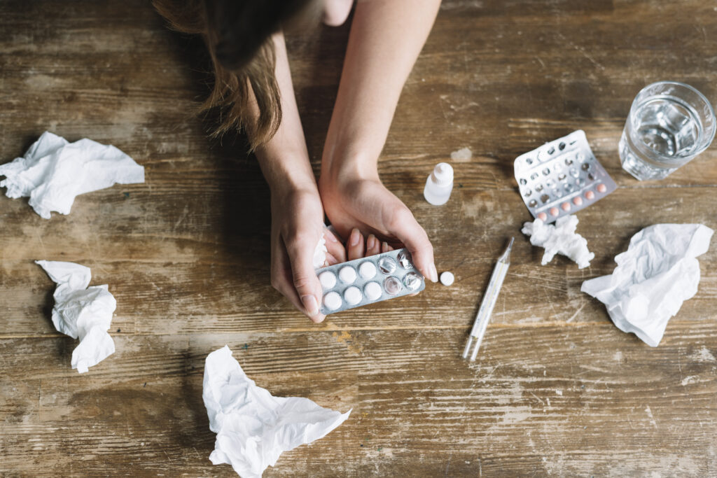 Woman holding medication packets and surrounded by tissues, depicting the challenge of substance abuse addressed in addiction treatment in Thousand Oaks CA.